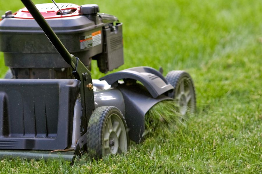 Push lawn mower cutting grass with side discharge open