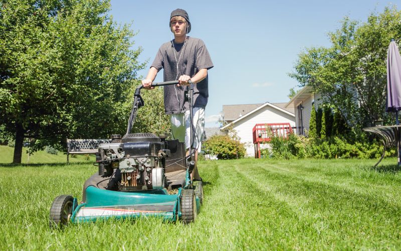 A teenage boy mowing lawn