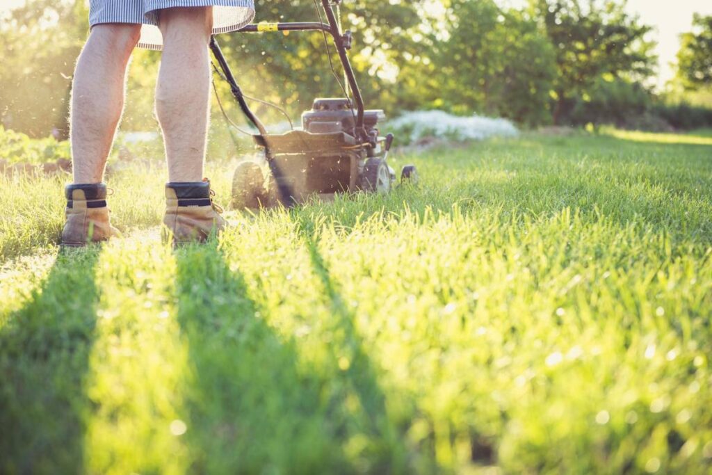 Close up of a man’s legs while mowing a lawn